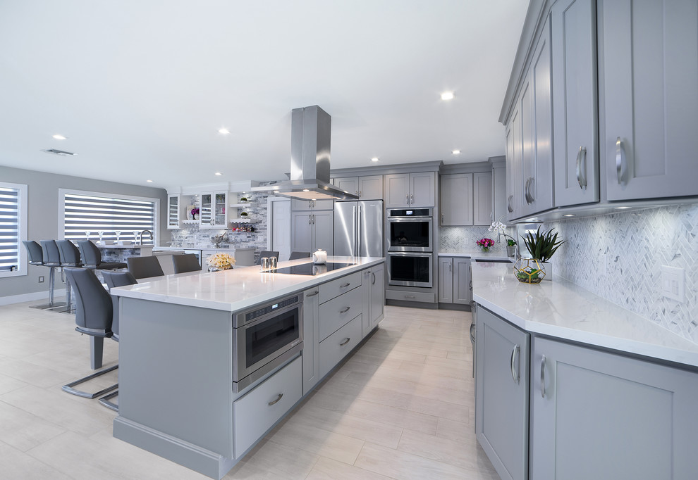 Inspiration for a large transitional l-shaped porcelain tile and gray floor open concept kitchen remodel in Miami with a farmhouse sink, shaker cabinets, gray cabinets, quartz countertops, gray backsplash, marble backsplash, stainless steel appliances and two islands