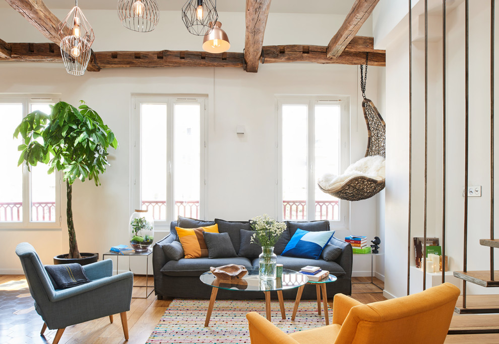 Photo of an eclectic living room in Paris with white walls, medium hardwood flooring, brown floors and exposed beams.