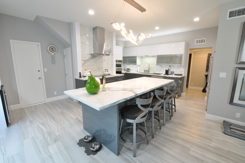 Photo of a large contemporary eat-in kitchen in Los Angeles with flat-panel cabinets, white cabinets, granite benchtops, white splashback, stone slab splashback, stainless steel appliances, light hardwood floors and with island.