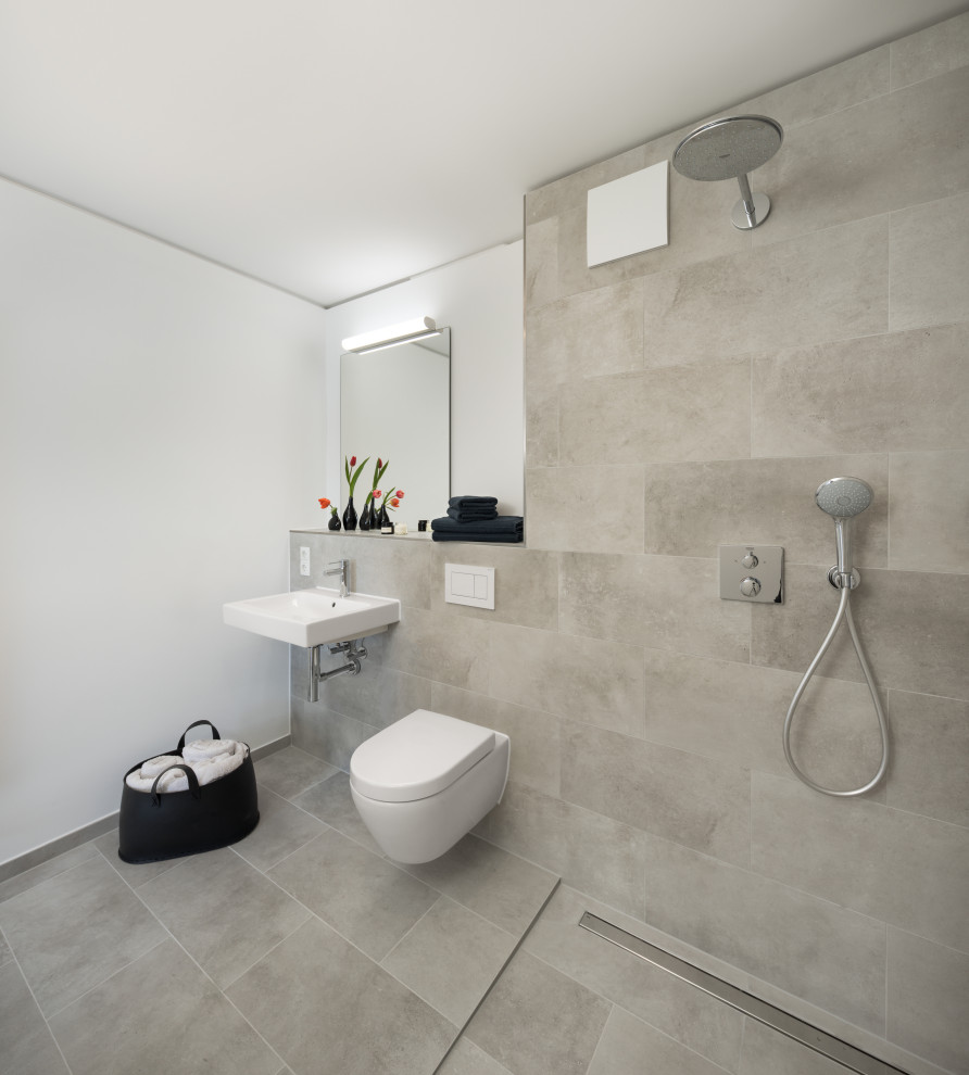 Modernes Badezimmer mit bodengleicher Dusche, Wandtoilette, grauen Fliesen, Steinfliesen, grauer Wandfarbe, Wandwaschbecken und Einzelwaschbecken in München