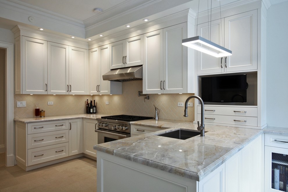 Example of a large transitional u-shaped limestone floor and beige floor enclosed kitchen design in Toronto with an undermount sink, recessed-panel cabinets, white cabinets, granite countertops, beige backsplash, ceramic backsplash, paneled appliances and a peninsula