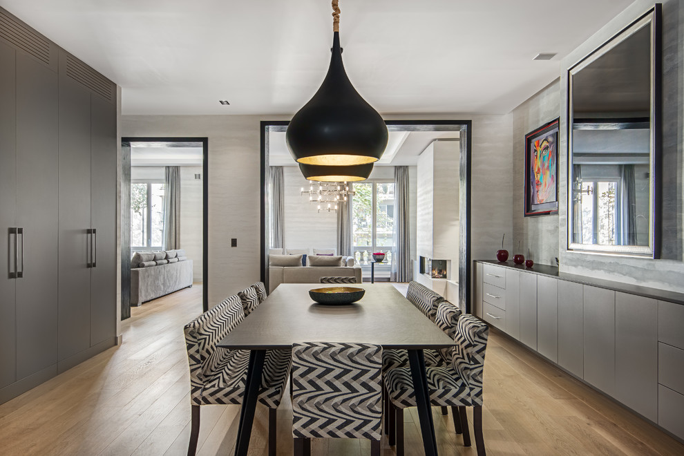 This is an example of a large contemporary open plan dining in Paris with beige walls and light hardwood floors.