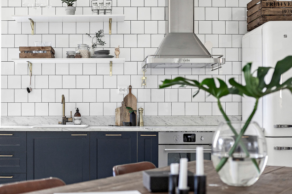 Industrial open plan kitchen in Stockholm with white floor.