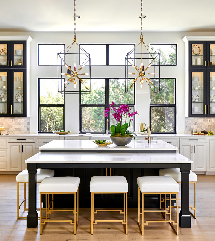 Inspiration for a large traditional kitchen in Austin with black cabinets, quartz benchtops, marble splashback, stainless steel appliances, light hardwood floors, with island, white benchtop and raised-panel cabinets.