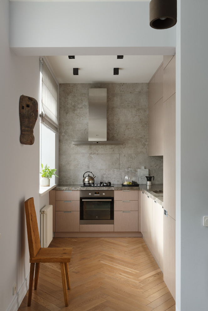 Photo of a contemporary l-shaped separate kitchen in Moscow with flat-panel cabinets, light wood cabinets, grey splashback, stainless steel appliances, medium hardwood floors, no island, cement tile splashback and brown floor.