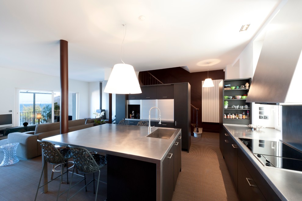Large contemporary u-shaped open plan kitchen in Marseille with an integrated sink, flat-panel cabinets, black cabinets, carpet and with island.