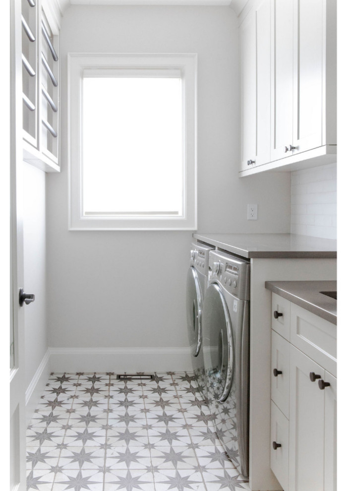 Inspiration for a mid-sized transitional galley dedicated laundry room in Toronto with an integrated sink, flat-panel cabinets, white cabinets, quartz benchtops, white splashback, subway tile splashback, white walls, a side-by-side washer and dryer, white floor and grey benchtop.