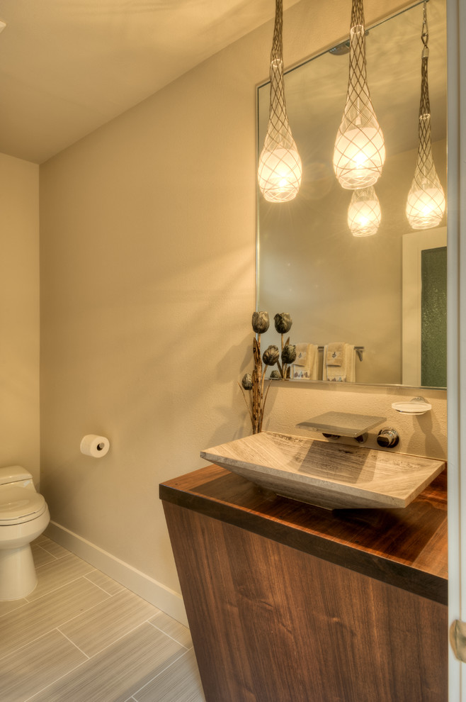 Inspiration for a small contemporary bathroom in Seattle with a vessel sink, open cabinets, dark wood cabinets, wood benchtops, beige tile, porcelain tile, beige walls and porcelain floors.