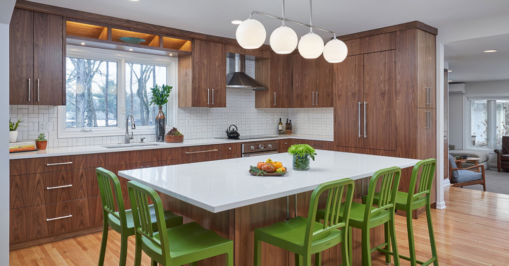 Photo of a mid-sized midcentury l-shaped kitchen in Minneapolis with an undermount sink, flat-panel cabinets, medium wood cabinets, white splashback, ceramic splashback, panelled appliances, light hardwood floors, with island, brown floor and white benchtop.