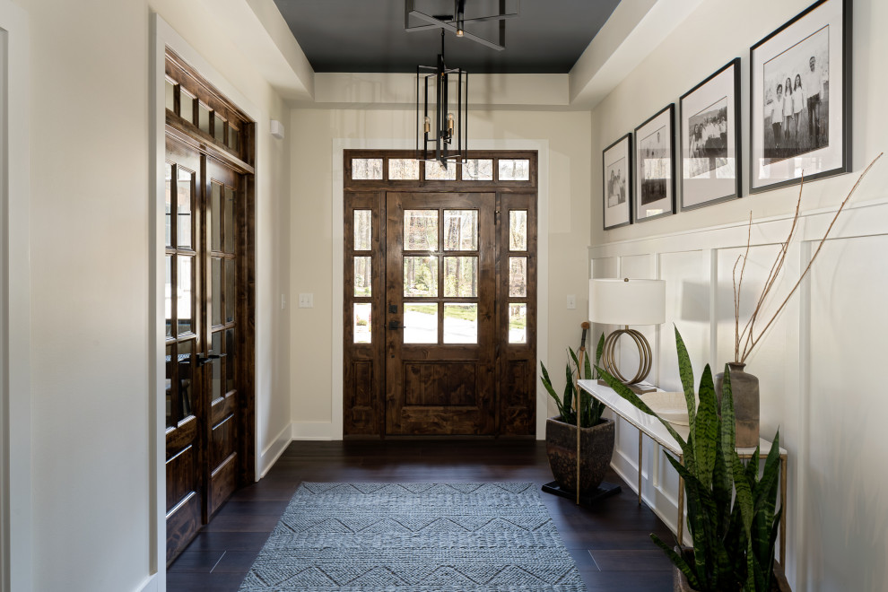 他の地域にあるトランジショナルスタイルのおしゃれな玄関ロビー (ベージュの壁、無垢フローリング、濃色木目調のドア、折り上げ天井、羽目板の壁) の写真