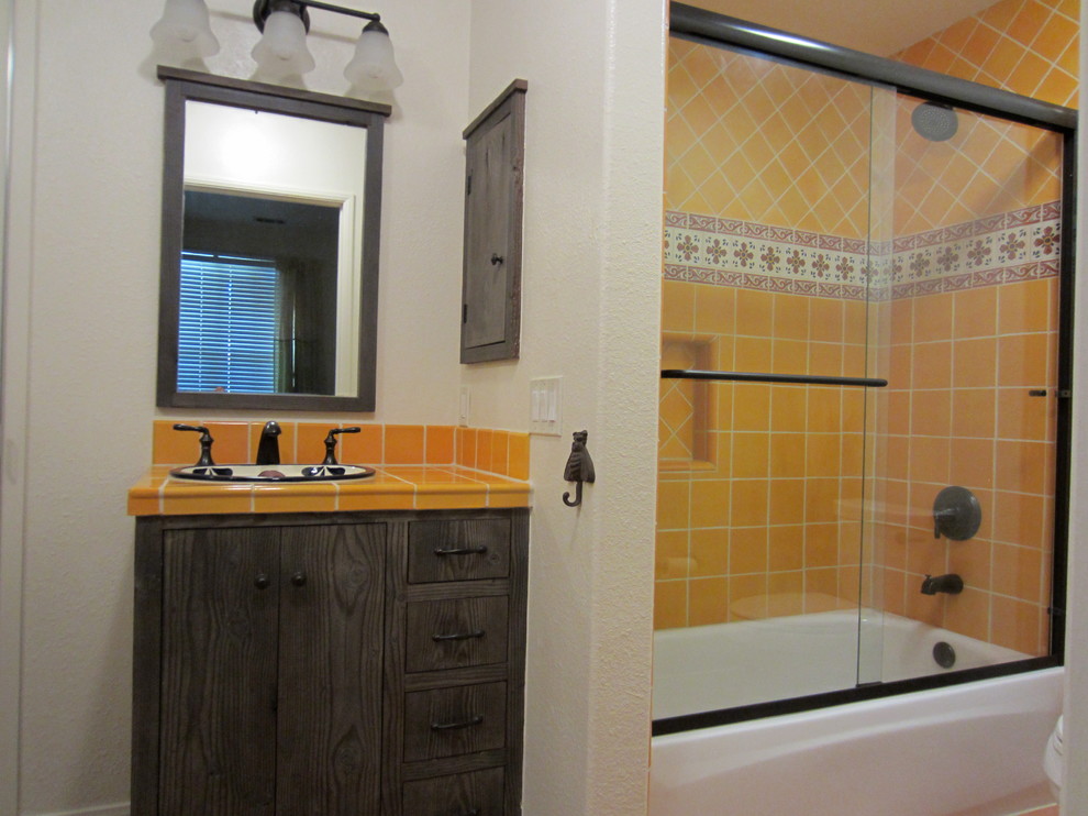 Small country master bathroom in San Diego with a drop-in sink, flat-panel cabinets, distressed cabinets, tile benchtops, an alcove tub, a shower/bathtub combo, a two-piece toilet, yellow tile, ceramic tile and beige walls.