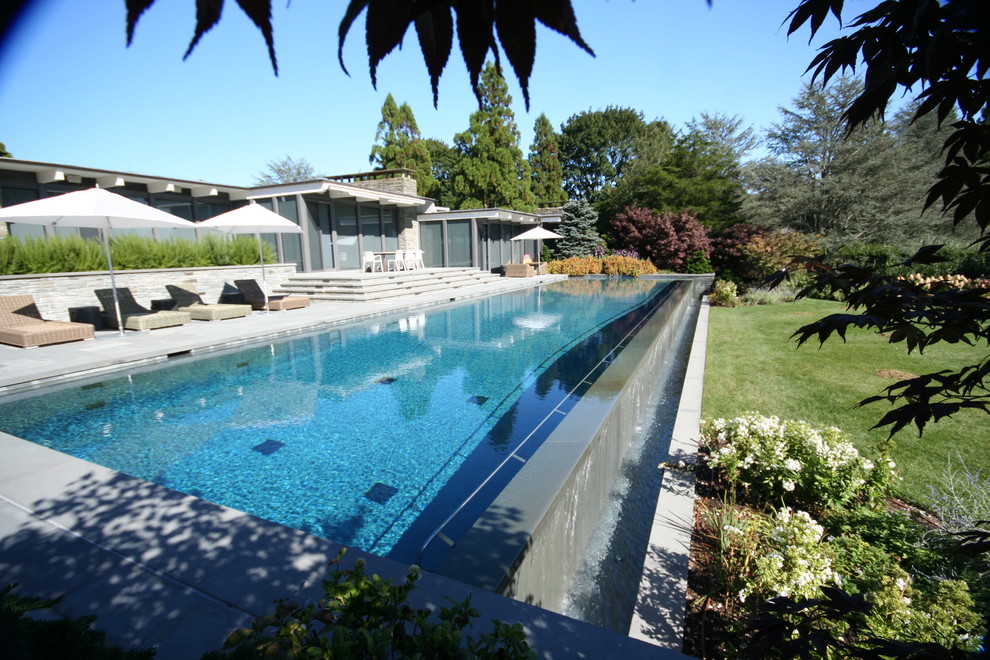 This is an example of a contemporary infinity pool in New York with natural stone pavers.