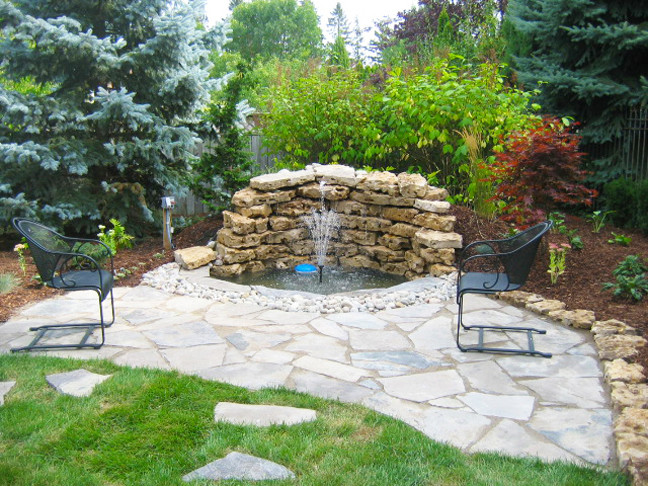 Inspiration for a transitional backyard stone patio fountain remodel in Toronto with no cover