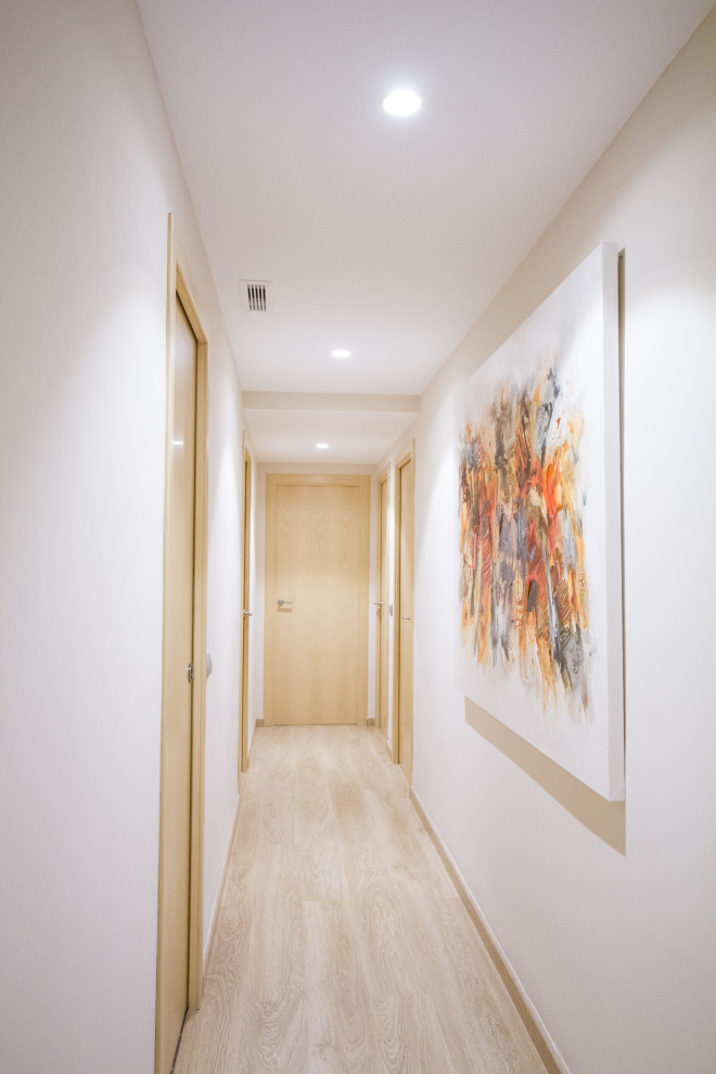 This is an example of a mid-sized contemporary hallway in Other with beige walls and laminate floors.