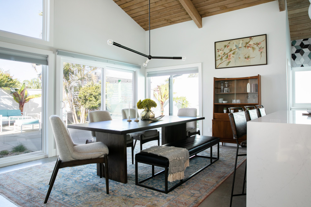 Стильный дизайн: кухня-столовая среднего размера в стиле ретро с белыми стенами, бетонным полом, угловым камином, фасадом камина из кирпича, серым полом и балками на потолке - последний тренд