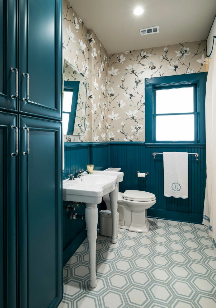 Immagine di un bagno di servizio american style di medie dimensioni con WC a due pezzi, pareti blu, pavimento con piastrelle in ceramica, lavabo a colonna, pavimento multicolore, mobile bagno freestanding e carta da parati