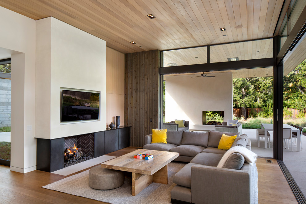 Photo of a contemporary living room in San Francisco with multi-coloured walls, light hardwood floors, a standard fireplace and a wall-mounted tv.