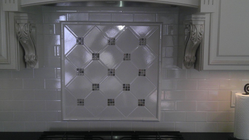 Example of a mid-sized l-shaped light wood floor eat-in kitchen design in Newark with a drop-in sink, raised-panel cabinets, white cabinets, granite countertops, white backsplash, subway tile backsplash, stainless steel appliances and an island