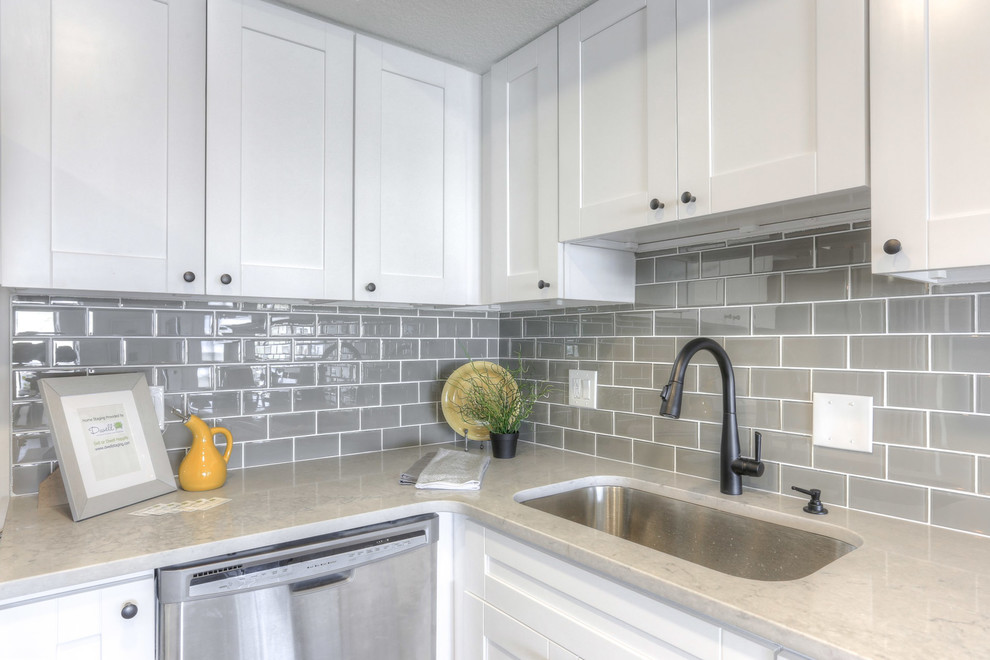 Mid-sized transitional l-shaped eat-in kitchen in Tampa with a single-bowl sink, shaker cabinets, white cabinets, quartz benchtops, grey splashback, glass tile splashback, stainless steel appliances, porcelain floors and no island.