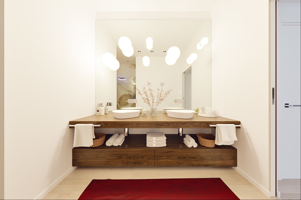 This is an example of a large contemporary 3/4 bathroom in Milan with light wood cabinets, an open shower, a wall-mount toilet, multi-coloured walls, light hardwood floors, a vessel sink and wood benchtops.