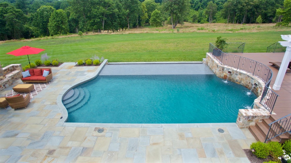 Ejemplo de piscina con fuente infinita tradicional grande rectangular en patio trasero con adoquines de piedra natural
