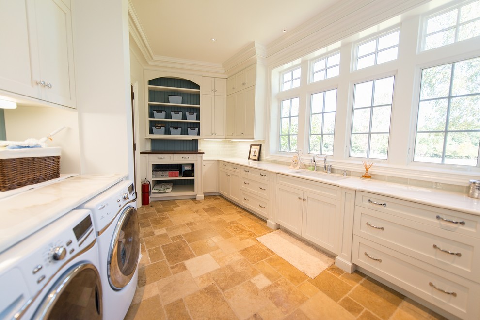 Inspiration for an expansive traditional galley utility room in New York with an undermount sink, shaker cabinets, white cabinets, marble benchtops, white walls, porcelain floors and a side-by-side washer and dryer.