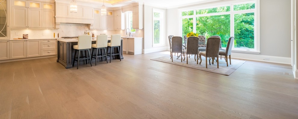 Inspiration for a large transitional l-shaped medium tone wood floor and brown floor open concept kitchen remodel in Orange County with an undermount sink, recessed-panel cabinets, white cabinets, quartzite countertops, white backsplash, stone slab backsplash, an island and white countertops