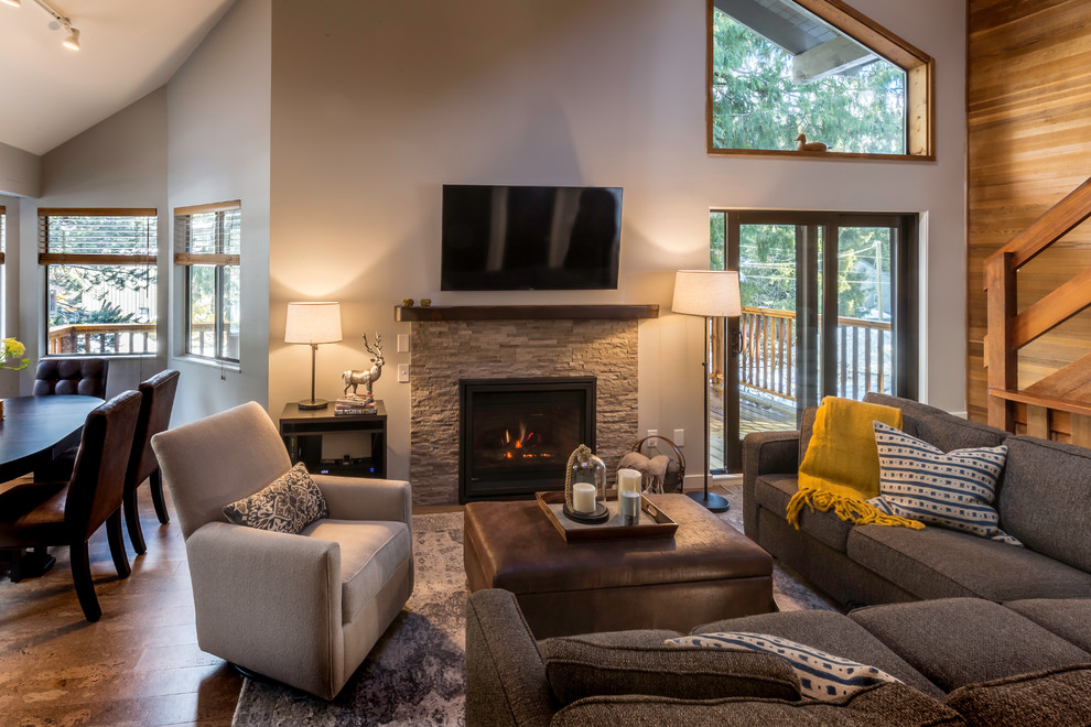 Photo of a mid-sized country open concept living room in Vancouver with grey walls, light hardwood floors, a standard fireplace, a stone fireplace surround, a wall-mounted tv and beige floor.