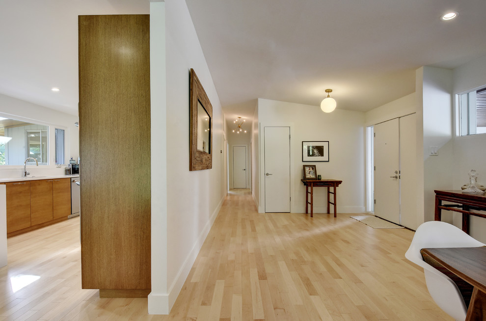 Photo of a large midcentury hallway in Austin with white walls, light hardwood floors and beige floor.