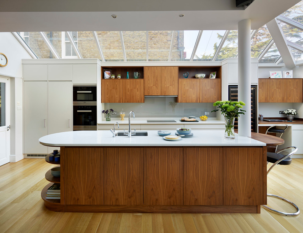 This is an example of an expansive contemporary open plan kitchen in London with grey splashback, with island, flat-panel cabinets and quartzite benchtops.