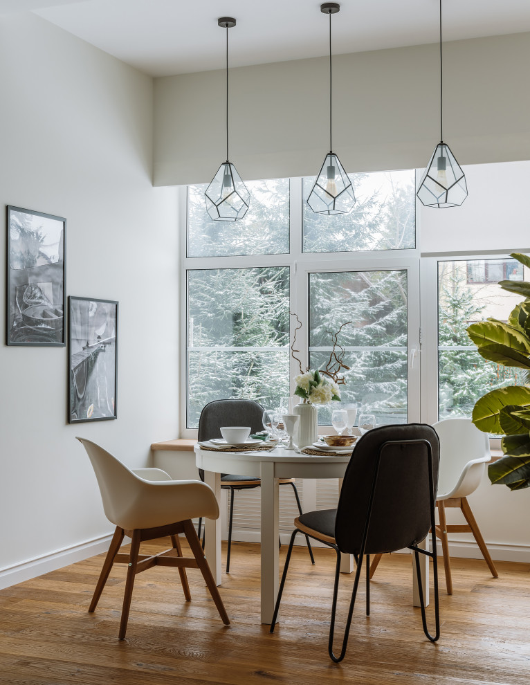This is an example of a large scandinavian separate dining room in Moscow with white walls and medium hardwood floors.