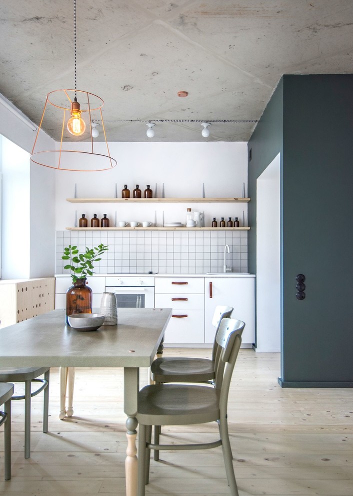 Photo of a small industrial single-wall eat-in kitchen in Saint Petersburg with light hardwood floors, a drop-in sink, flat-panel cabinets, white cabinets, white splashback, white appliances and no island.