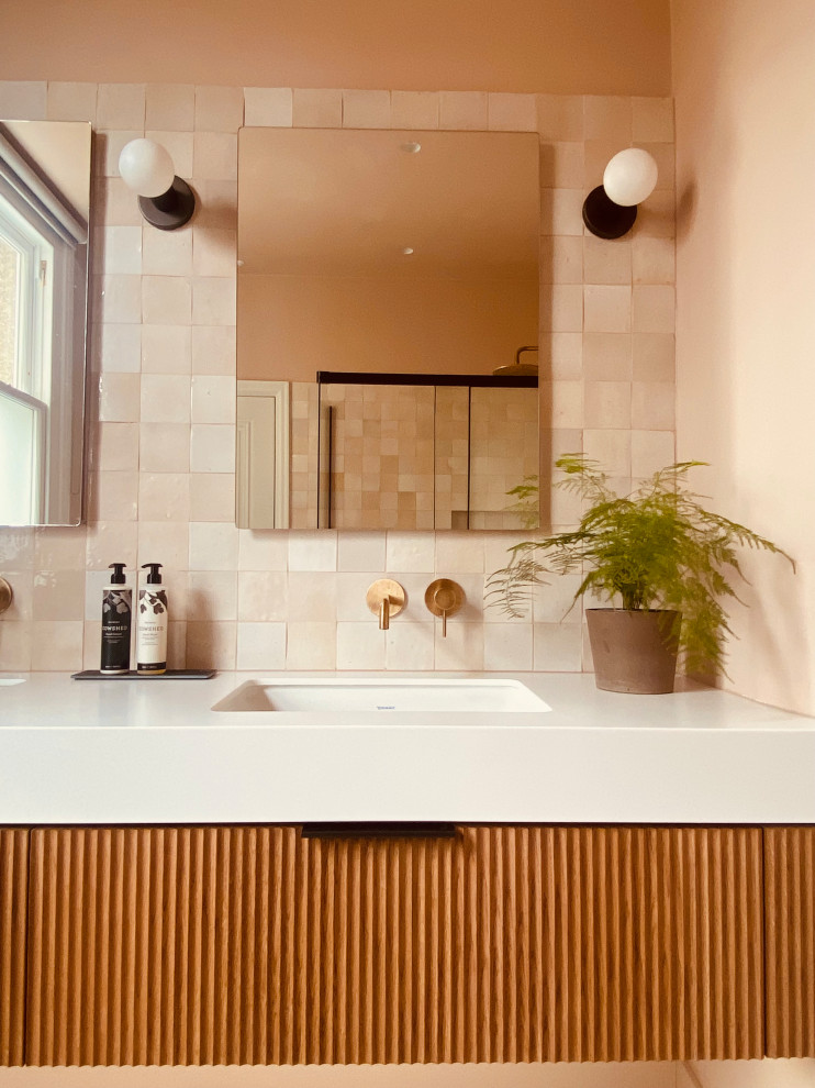 Large modern master wet room bathroom in London with beaded inset cabinets, dark wood cabinets, a wall-mount toilet, pink tile, pink walls, porcelain floors, a wall-mount sink, grey floor, a sliding shower screen, white benchtops, a double vanity and a built-in vanity.