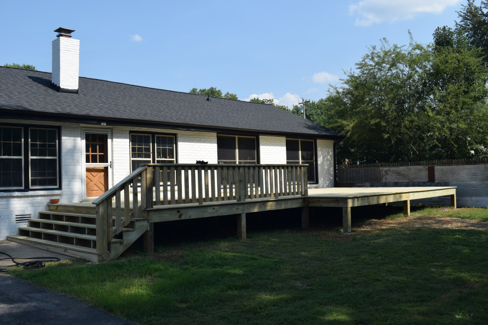 Deck - large backyard ground level wood railing deck idea with a roof extension
