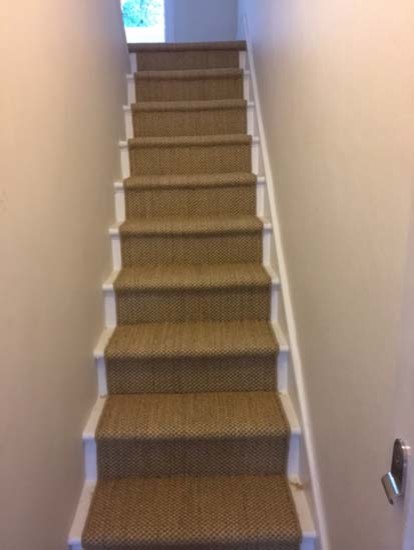 Photo of a country carpeted u-shaped staircase in London with carpet risers and wood railing.