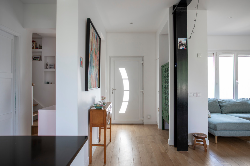 Idées déco pour une entrée contemporaine de taille moyenne avec un mur blanc, parquet clair, une porte simple, une porte blanche et un sol marron.