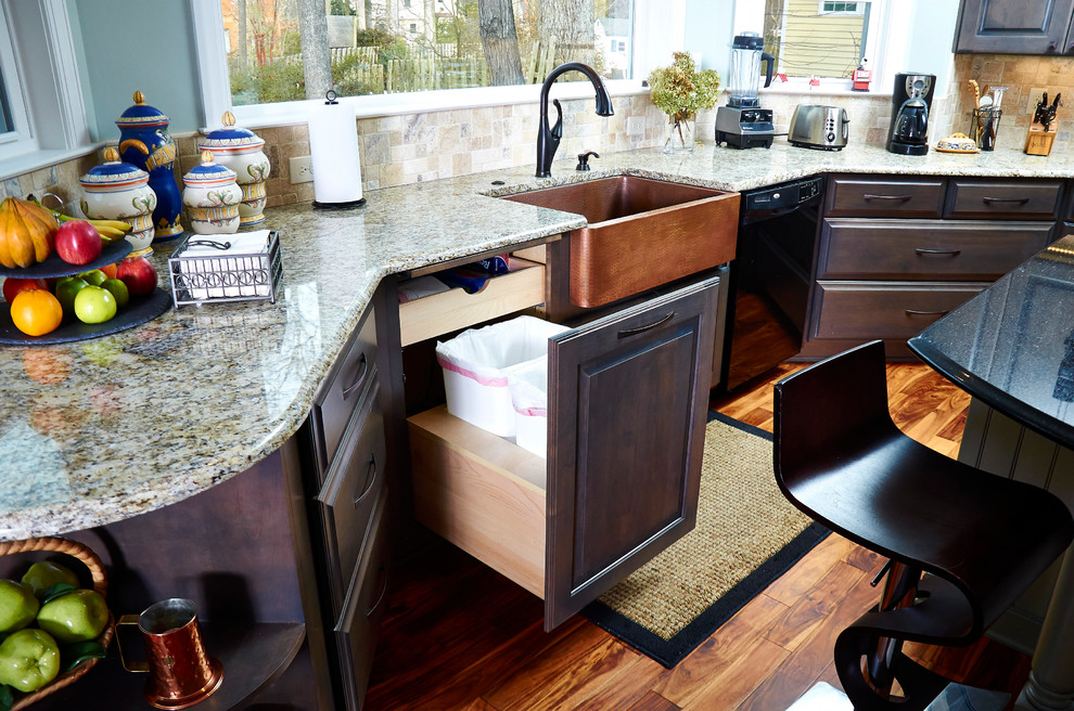 This is an example of an eclectic kitchen in Other with a drop-in sink, dark wood cabinets, granite benchtops, stainless steel appliances, medium hardwood floors and with island.