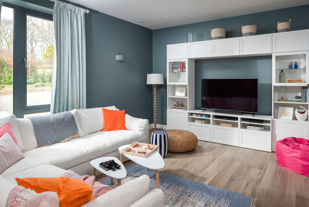 Imagen de sala de estar abierta marinera de tamaño medio con paredes blancas, suelo de madera clara, televisor independiente y suelo marrón