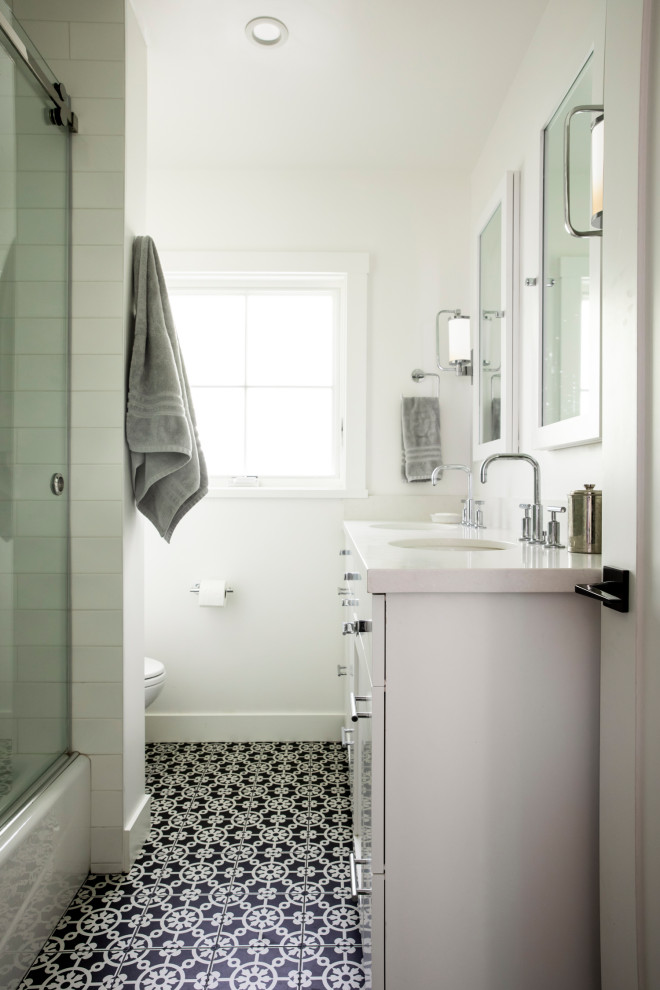 This is an example of a small country master bathroom in San Francisco with shaker cabinets, white cabinets, a shower/bathtub combo, a one-piece toilet, white walls, cement tiles, an undermount sink, engineered quartz benchtops, blue floor, a sliding shower screen, white benchtops, a double vanity and a built-in vanity.