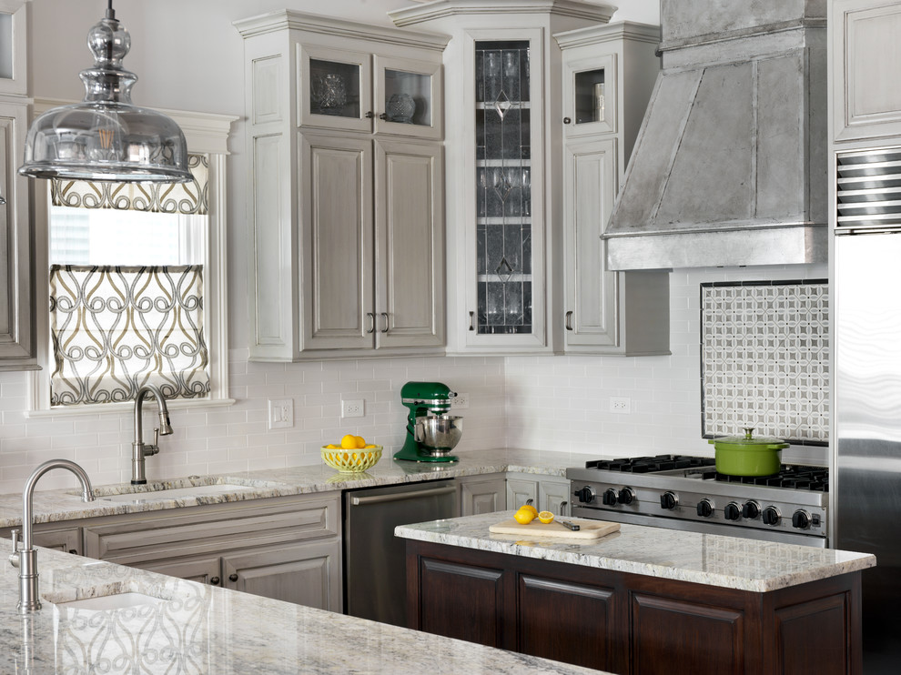Mid-sized transitional l-shaped dark wood floor and brown floor kitchen pantry photo in Boston with an undermount sink, raised-panel cabinets, gray cabinets, granite countertops, white backsplash, subway tile backsplash, stainless steel appliances and an island