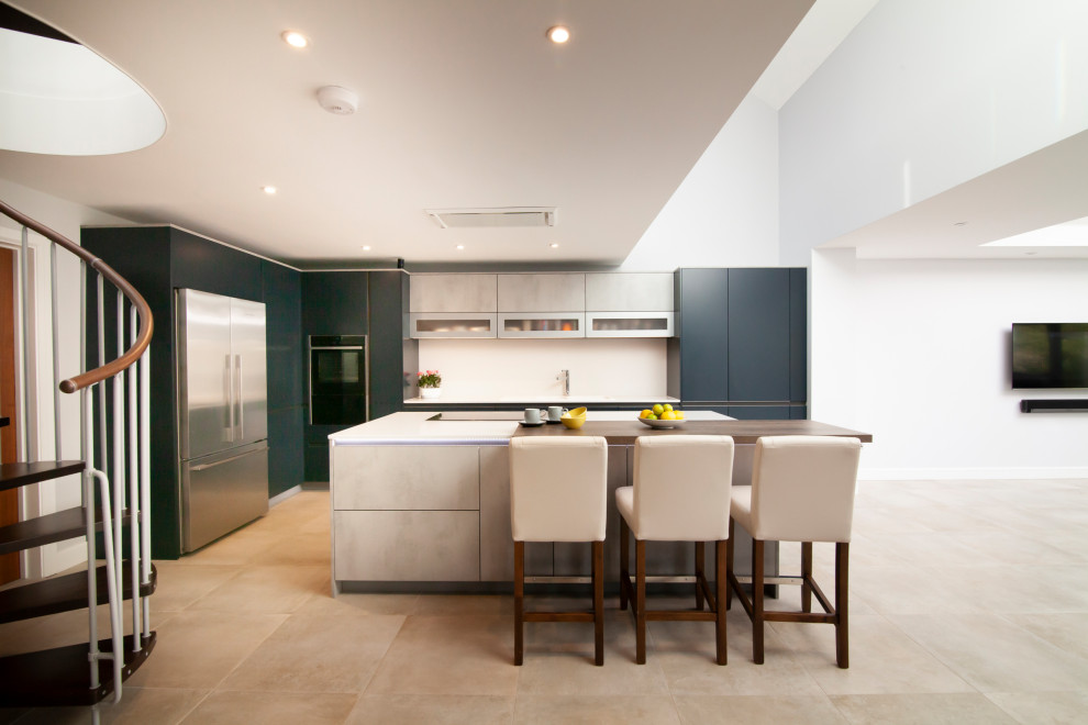 Design ideas for a mid-sized contemporary l-shaped open plan kitchen in Berkshire with a drop-in sink, flat-panel cabinets, blue cabinets, quartzite benchtops, black appliances, with island and white benchtop.