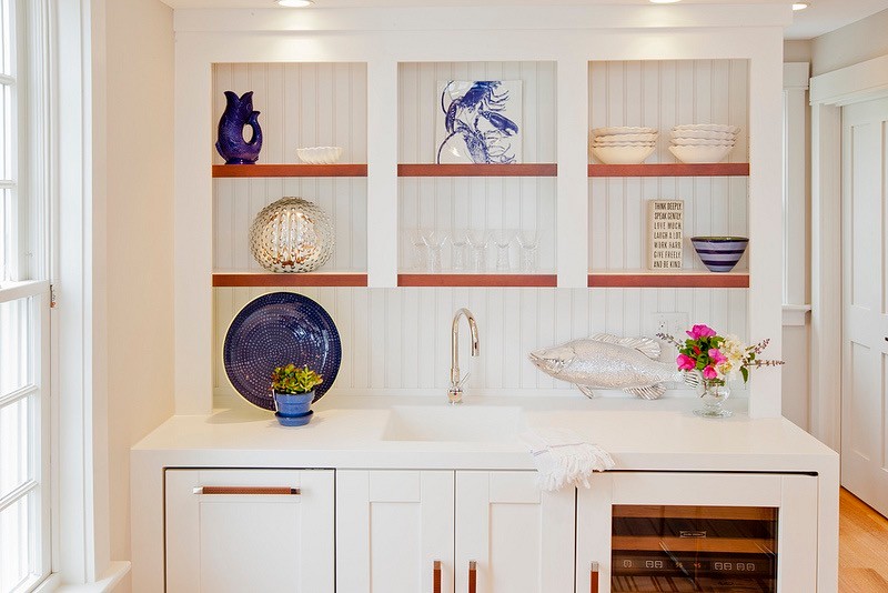 Photo of a small beach style single-wall wet bar in Portland Maine with an integrated sink, shaker cabinets, white cabinets, solid surface benchtops, white splashback, timber splashback and light hardwood floors.