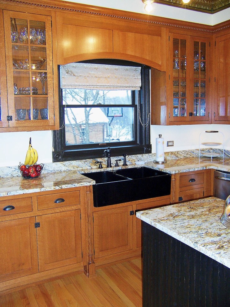 Country u-shaped kitchen in Chicago with a farmhouse sink, recessed-panel cabinets, medium wood cabinets, granite benchtops and stainless steel appliances.