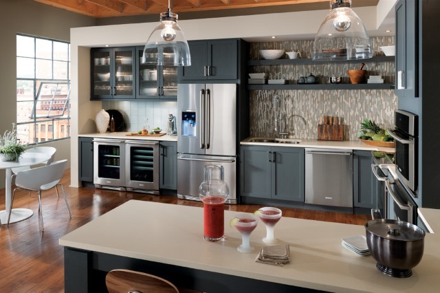 Inspiration for a large industrial u-shaped eat-in kitchen in New York with blue cabinets, granite benchtops, blue splashback, stainless steel appliances, medium hardwood floors, an undermount sink, shaker cabinets, glass tile splashback, a peninsula and brown floor.