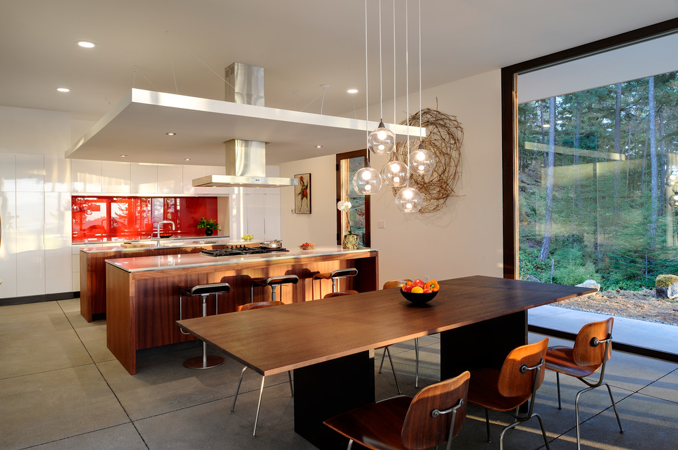 This is an example of a mid-sized contemporary galley eat-in kitchen in Seattle with flat-panel cabinets, a double-bowl sink, dark wood cabinets, solid surface benchtops, white splashback, stone slab splashback, stainless steel appliances, concrete floors and with island.