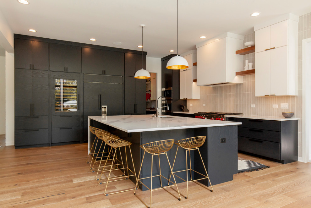 Example of a large minimalist l-shaped light wood floor and brown floor eat-in kitchen design in Chicago with an undermount sink, flat-panel cabinets, black cabinets, quartz countertops, beige backsplash, subway tile backsplash, paneled appliances, an island and white countertops