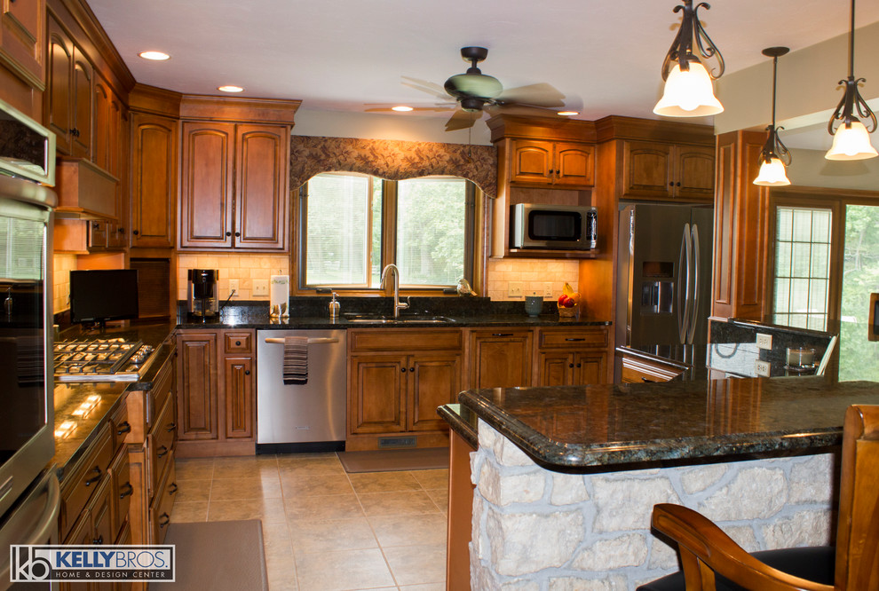 Inredning av ett lantligt stort kök, med luckor med upphöjd panel, skåp i mellenmörkt trä, granitbänkskiva, beige stänkskydd, stänkskydd i stenkakel, rostfria vitvaror och en köksö