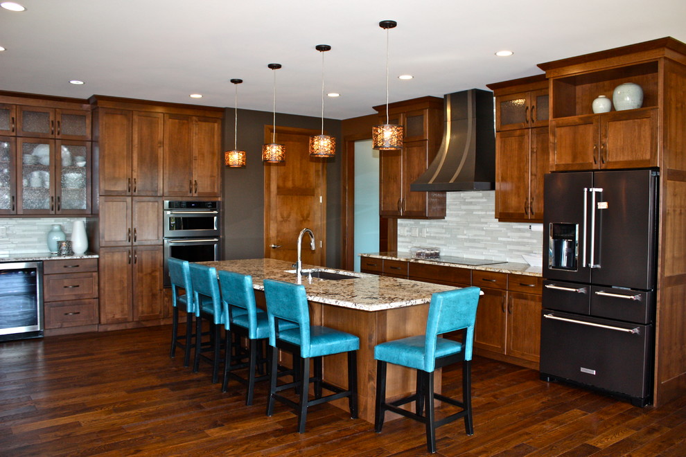 Open concept kitchen - large transitional l-shaped medium tone wood floor and brown floor open concept kitchen idea with an undermount sink, recessed-panel cabinets, medium tone wood cabinets, granite countertops, white backsplash, glass tile backsplash, stainless steel appliances and an island