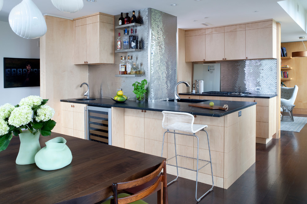 Photo of a mid-sized contemporary galley eat-in kitchen in Other with flat-panel cabinets, light wood cabinets, metallic splashback, metal splashback, an undermount sink, stainless steel appliances, dark hardwood floors, a peninsula and brown floor.