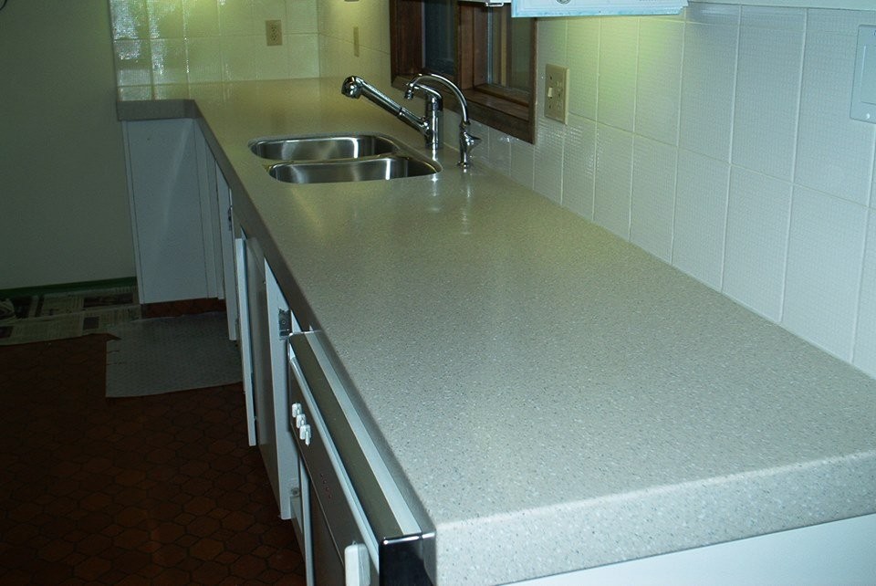Kitchen - transitional brown floor kitchen idea with a double-bowl sink, white cabinets, laminate countertops, white backsplash and stainless steel appliances